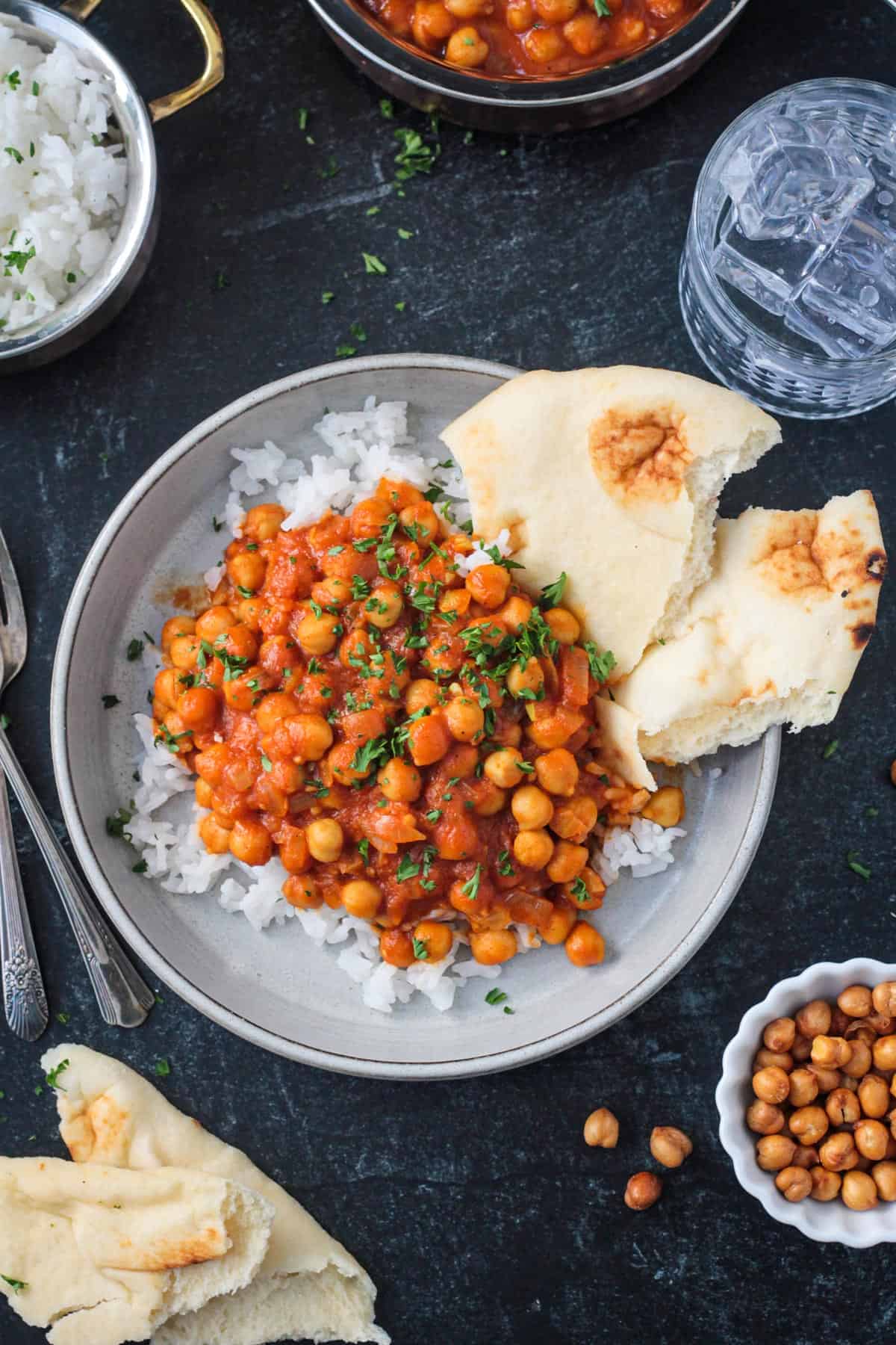 Chickpea tikka masala plated over rice with a side of naan.