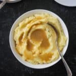 Bowl of mashed potatoes topped with vegan gravy.