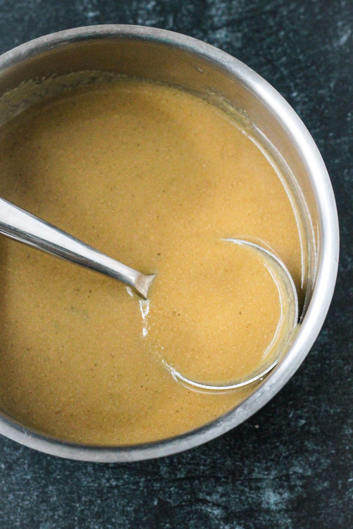 Ladle of gravy in a sauce pot.