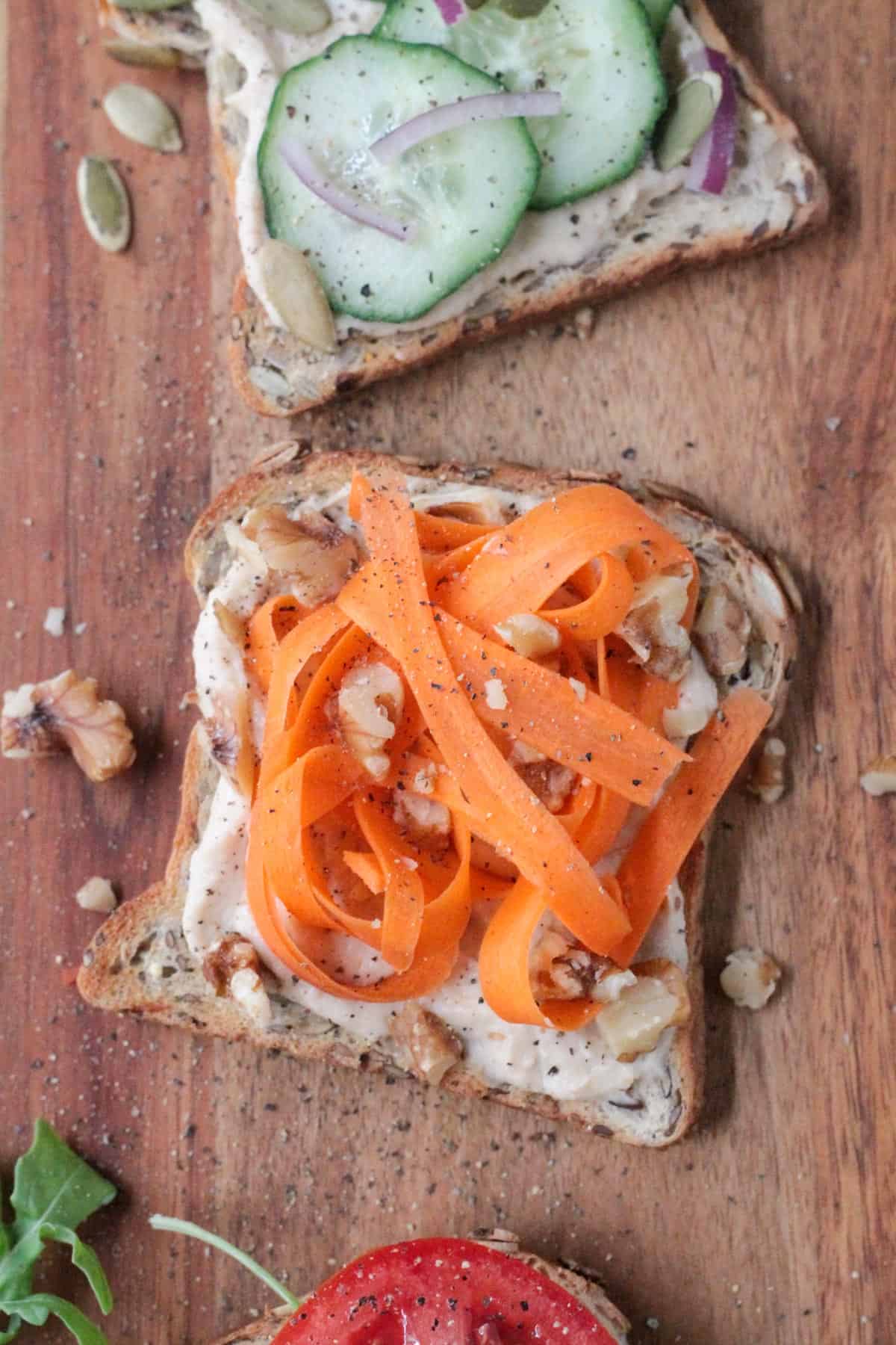 Hummus toast topped with carrot ribbons and chopped walnuts.
