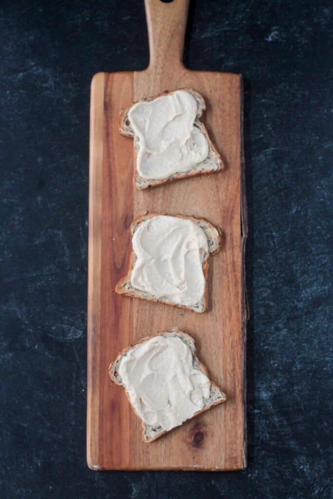 Three pieces of toast spread with hummus.