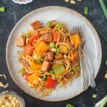 Kung Pao Tofu with noodles on a plate with two forks.
