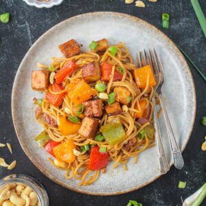 Kung Pao Tofu with noodles on a plate with two forks.