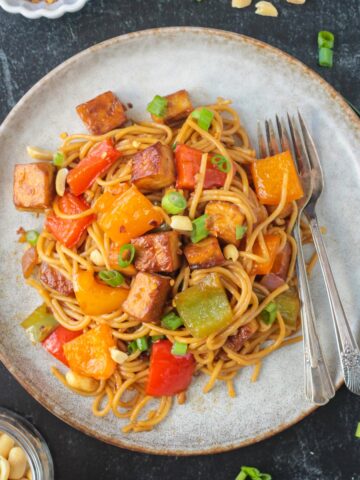 Kung Pao Tofu with noodles on a plate with two forks.