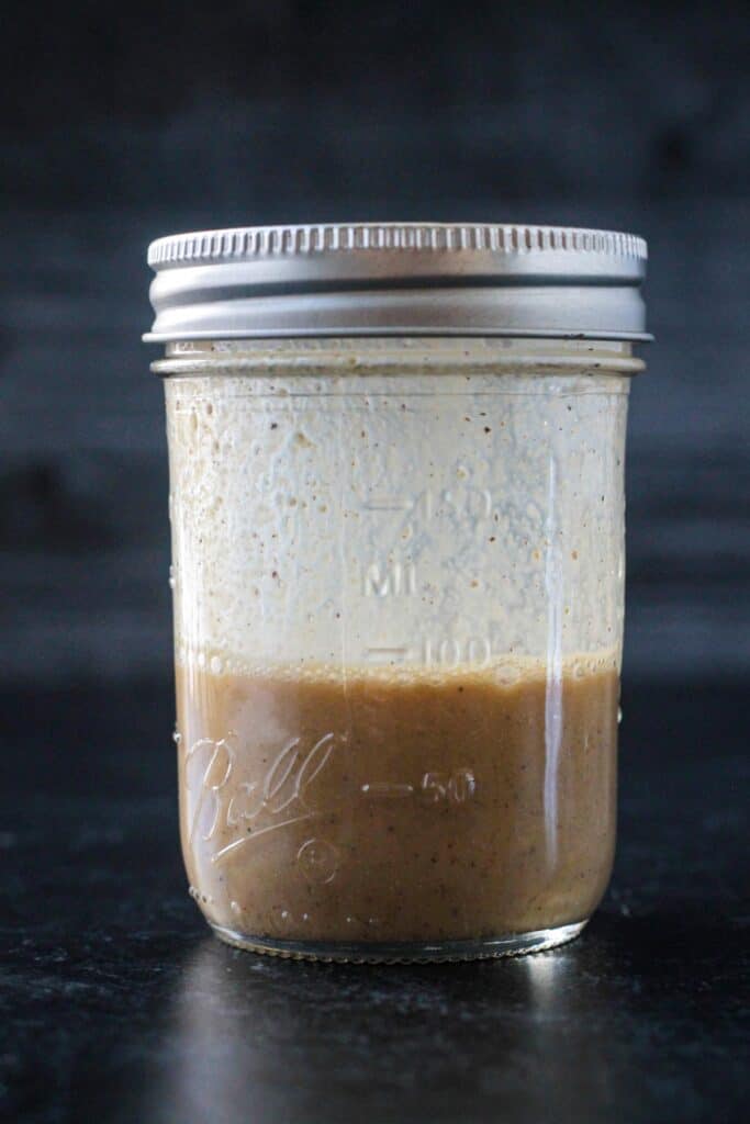 Dijon dressing in a glass jar with a lid.