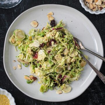 Shaved brussels sprouts salad on a plate with two forks.