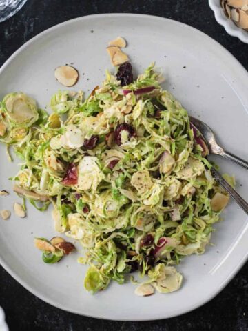 Shaved brussels sprouts salad on a plate with two forks.