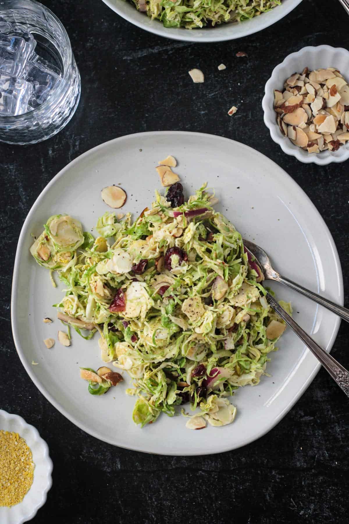 Shaved brussels sprouts salad on a plate with two forks.