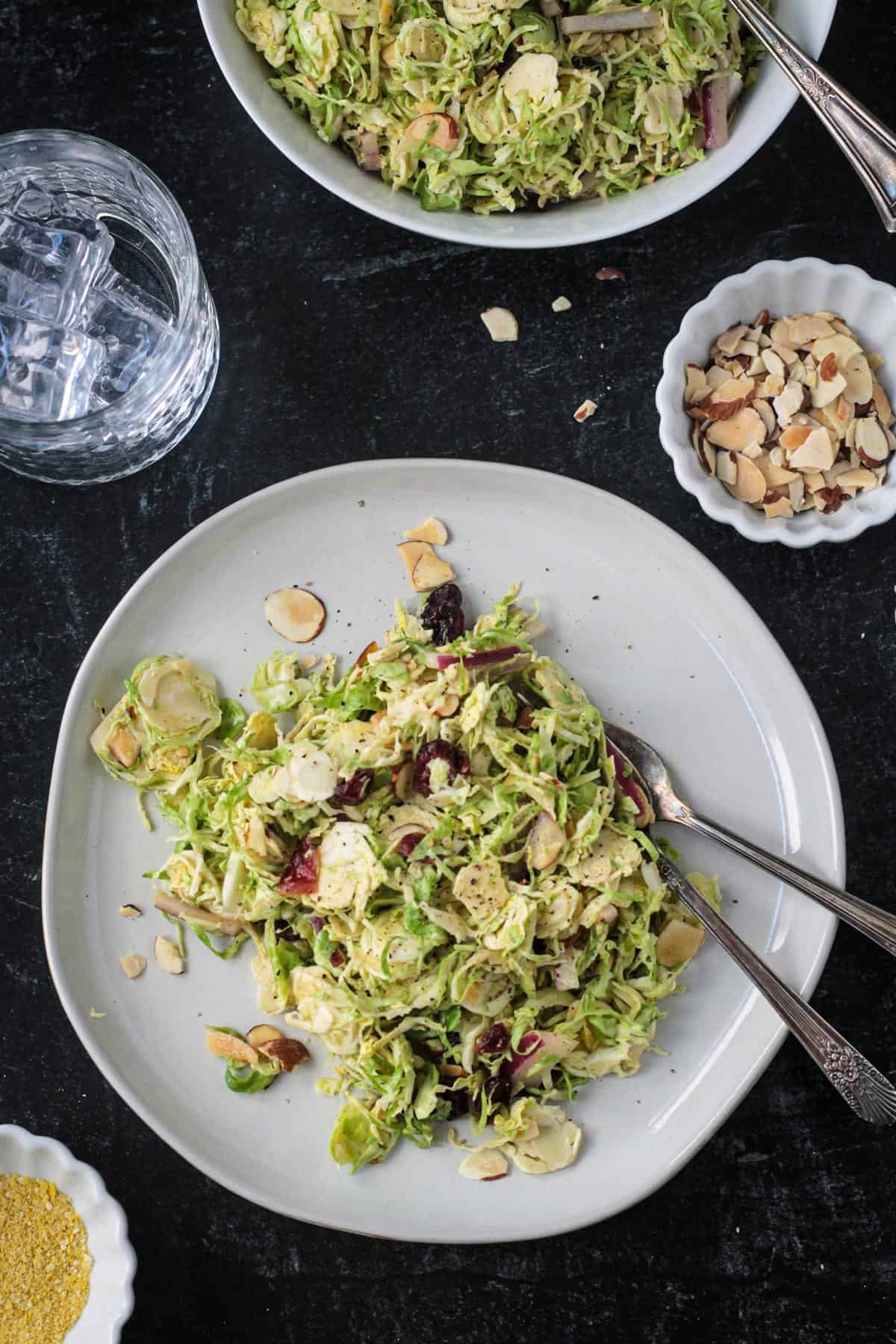 Shaved brussels sprouts salad on a plate with two forks.