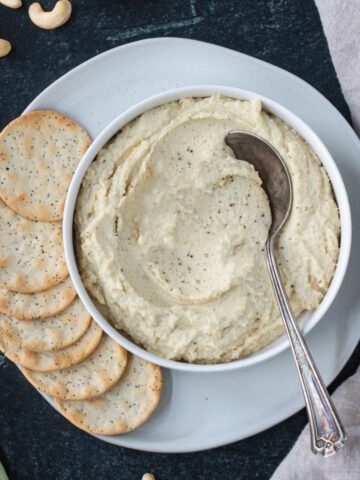 Vegan ricotta in a serving bowl on a plate with crackers.
