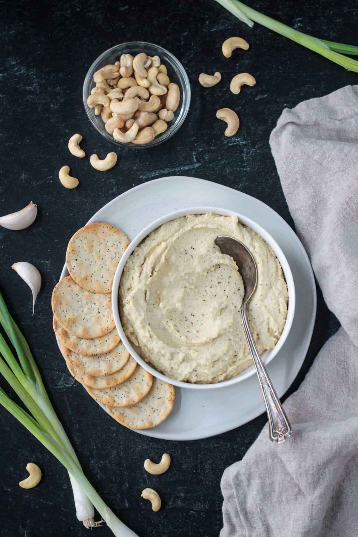 Vegan ricotta in a serving bowl on a plate with crackers.
