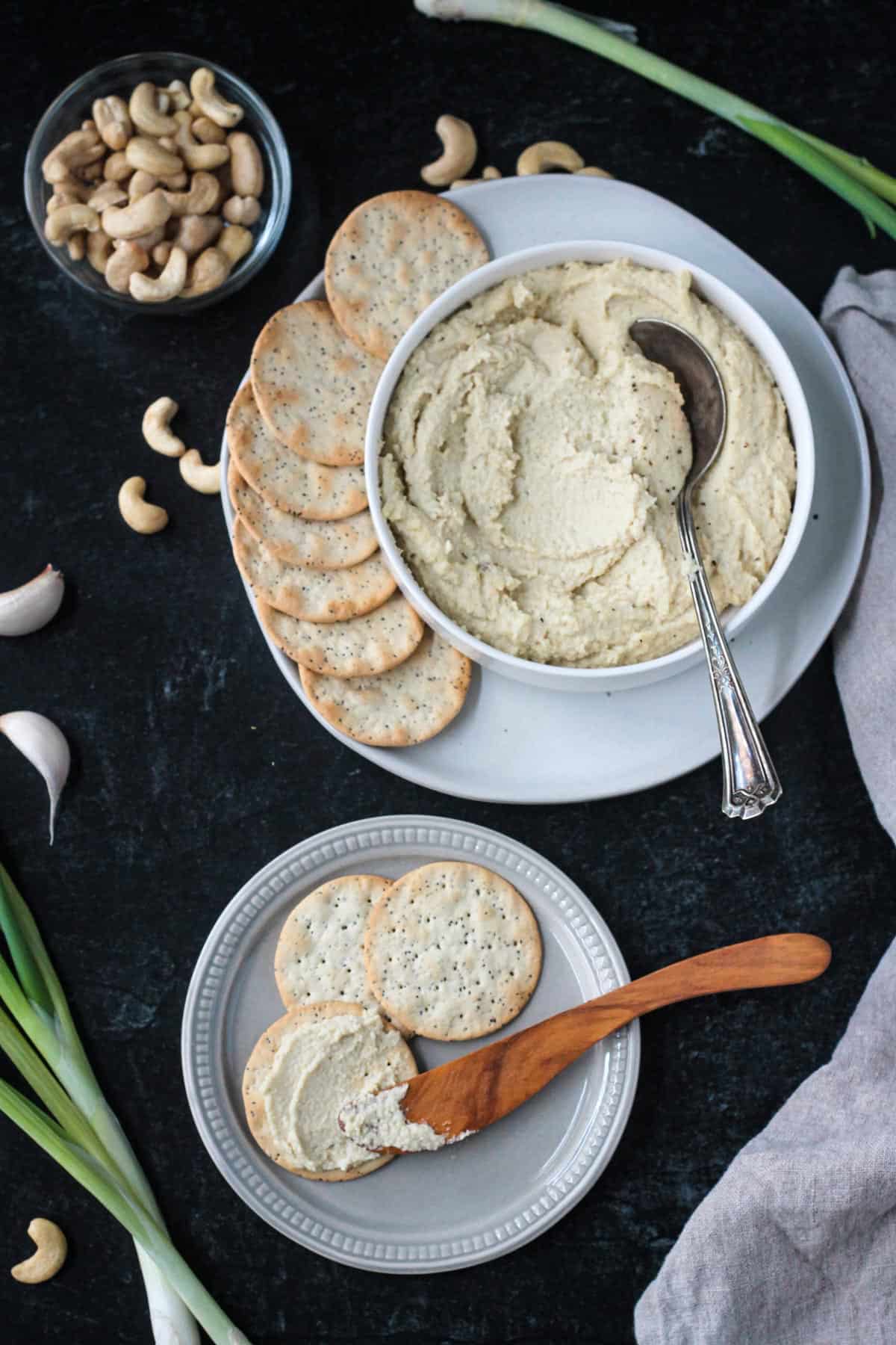 Bowl of ricotta spread next to a plate of crackers.