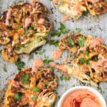 Four cauliflower steaks with a small bowl of harissa yogurt sauce.