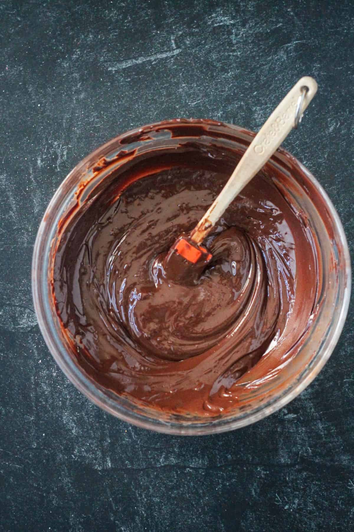 Melted chocolate in a bowl with a small silicone spatula.