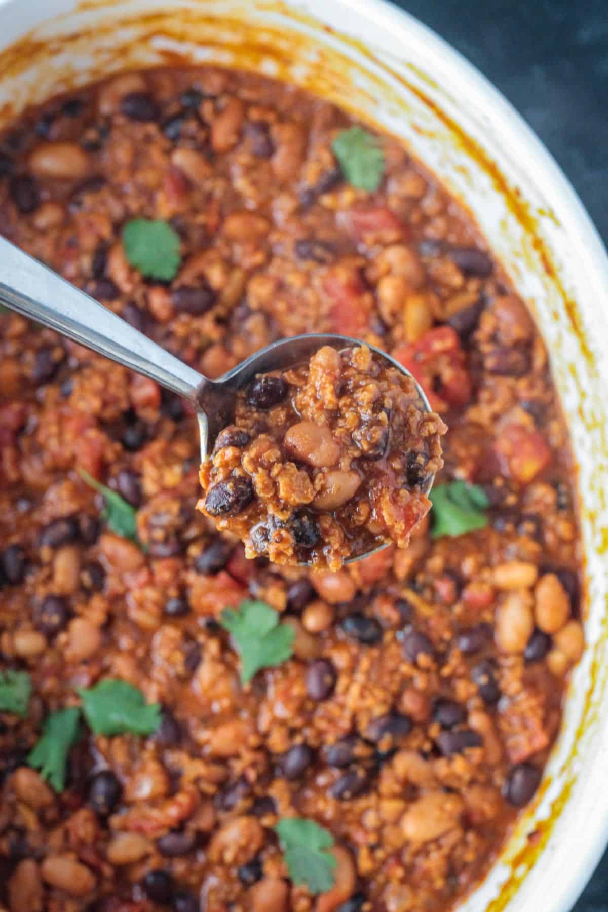 Ladle of chili being lifted from the pot.