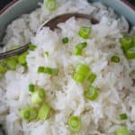 Fluffy coconut jasmine rice garnished with sliced green onions in a serving bowl.