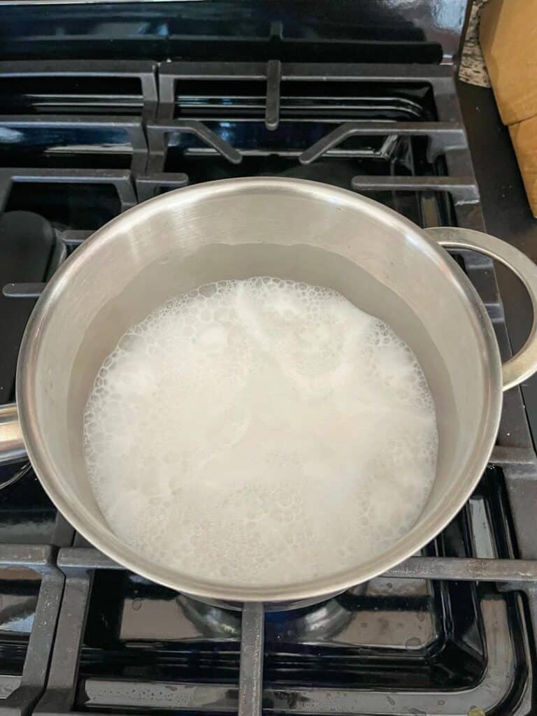 Coconut milk, water, and jasmine rice boiling in a pot.