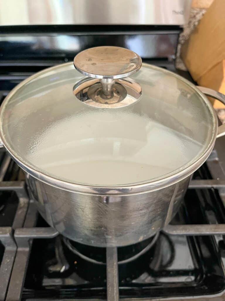 Rice cooking on the stove in a pot with a lid.