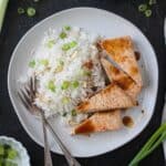 Coconut rice on a plate with triangles of baked tofu and two forks.