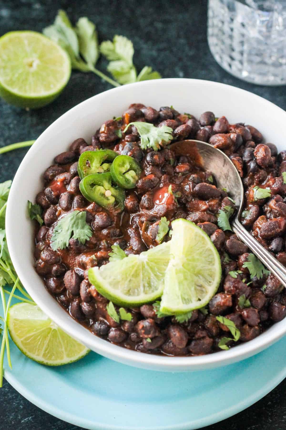 Metal serving spoon in a bowl of spicy seasoned black beans.