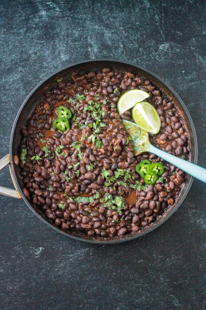 Canned black beans simmered with spices and garnished with chopped cilantro and sliced jalapeños.