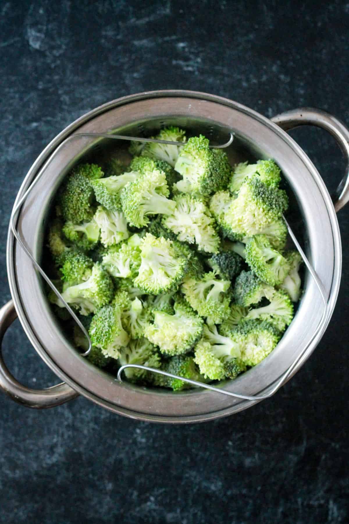 Chopped raw broccoli in a steamer pot.