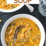 Metal spoon in a bowl of creamy vegetable soup.