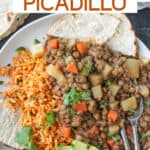 Vegan lentil picadillo on a plate with Mexican red rice, avocado, and corn tortillas.