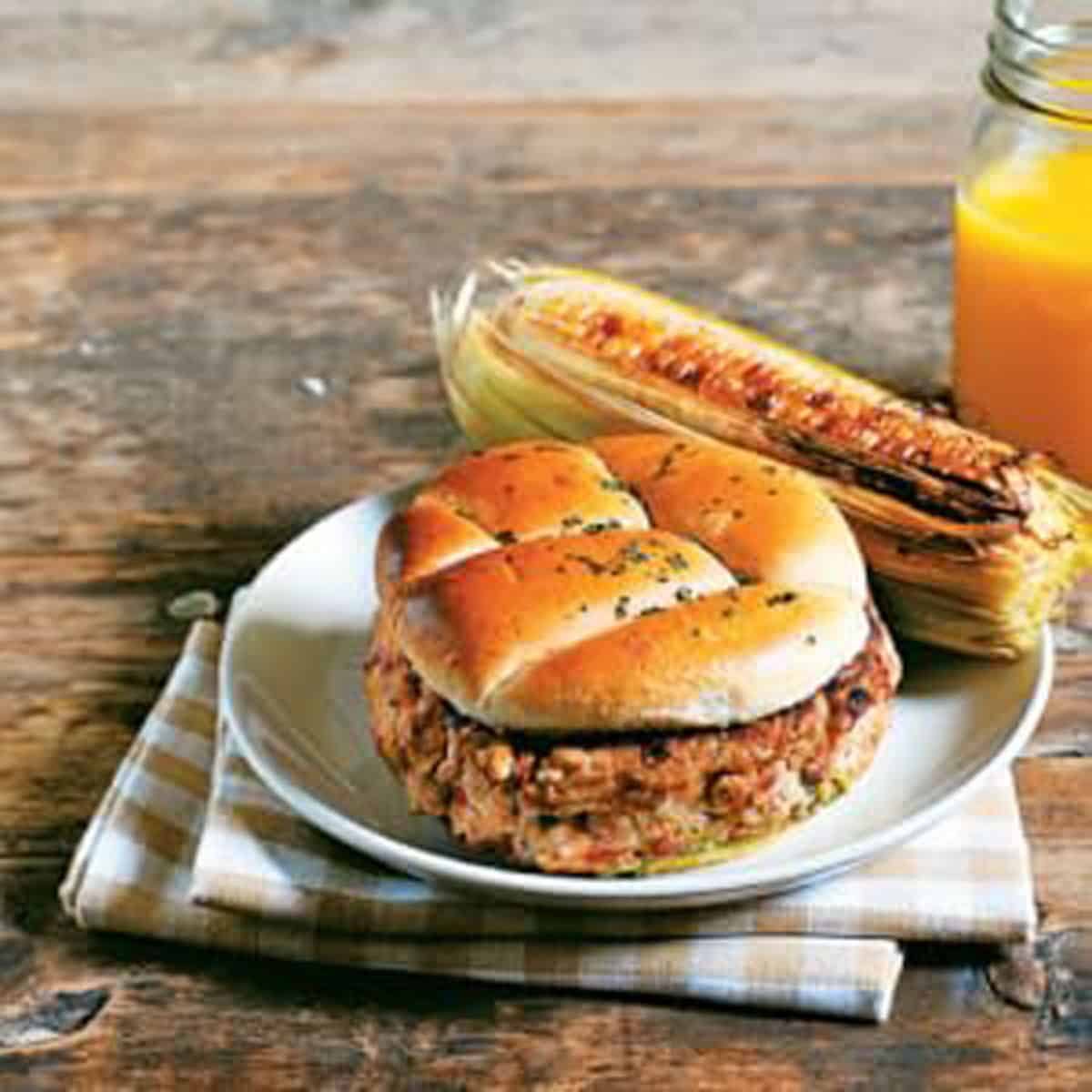 Veggie burger on a place with corn on the cob.